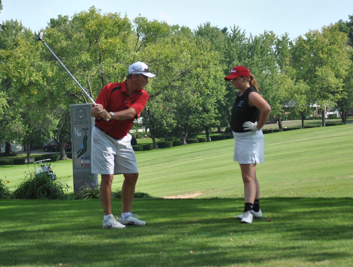 Coach Pannett helps sophomore, Molly Pannett with her golf swing.