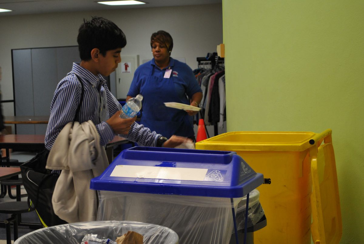 A sixth grade student at Northeast Middle sorts his trash after lunch. Middle and elementary school students are taught which materials go in which bins. Photo by Julia Goldman.