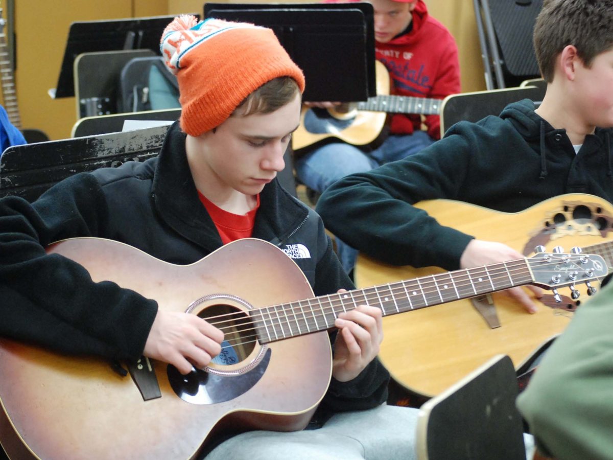 Freshman Connor Hank tunes his guitar during Mr. Beazleys Guitar 2 class. Photo by Clare Conlisk.