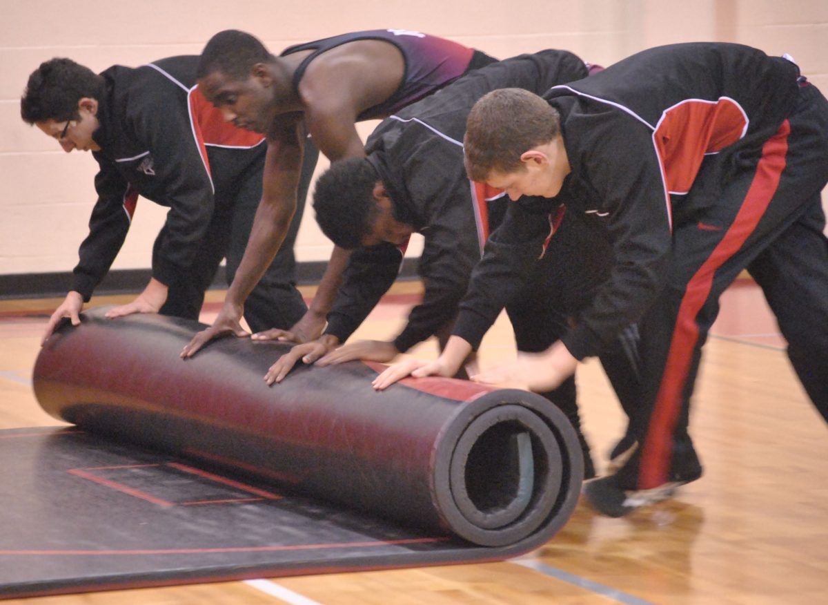 The wrestling team rolls up the mat as they finish up thier meet. Photo by Emily Schenberg
