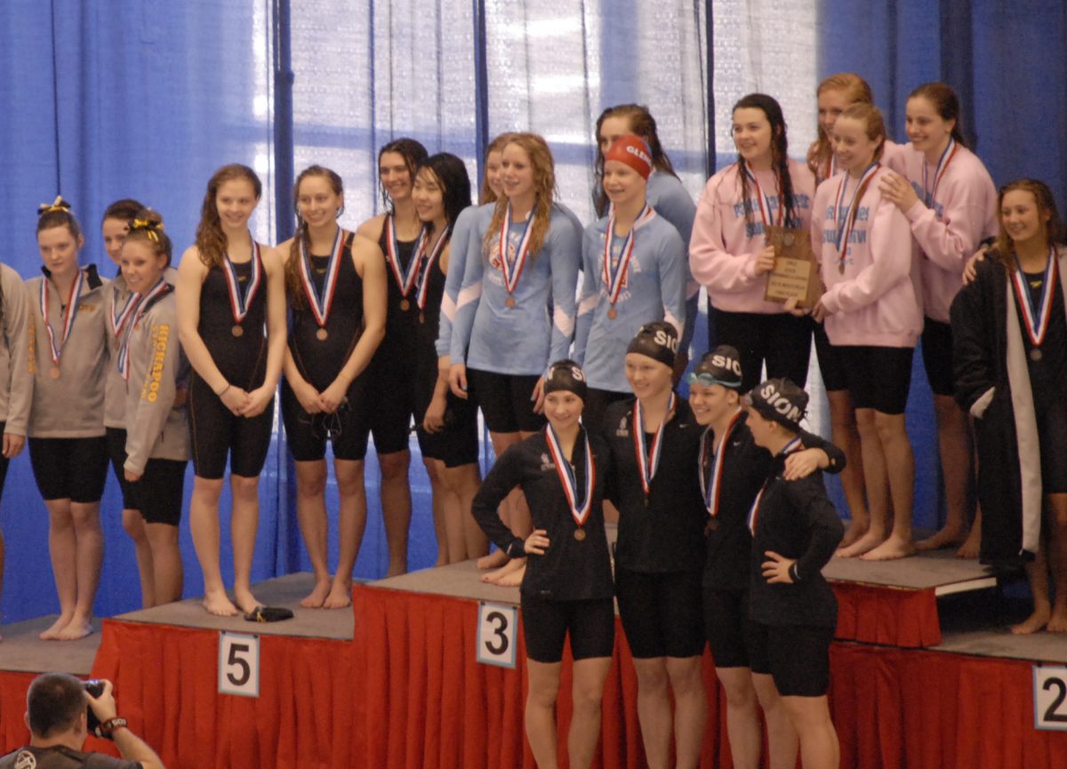The 200-yard medley relay of junior Elaine Reichert, senior Ally Neumann, and juniors Kelilah Liu and Courtney Nall stands on the podium. The relay finished in fifth place and set a new school record. Photo by Brandon Weissman.