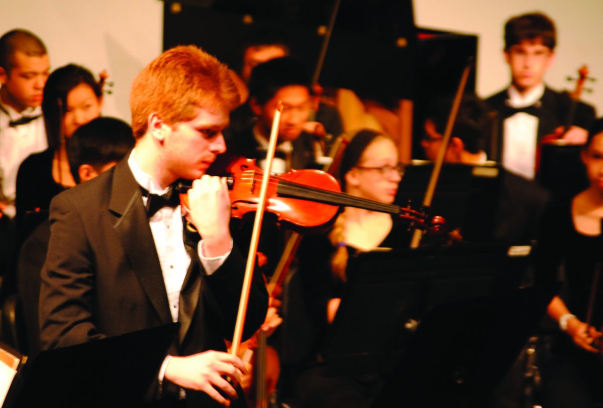 Senior Sean Byrne tunes his viola before the Winter Orchestra Concert on Nov. 13. Photo by Meaghan Flynn.
