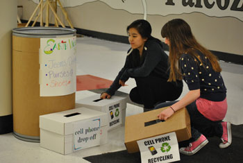 Juniors Julia Goldman and Sarah Kim set out bins for Earth Week. Students are encouraged to donate jeans, purses, shoes, cell phones and crayons from Apr. 15-19. Photo by Meaghan Flynn.
