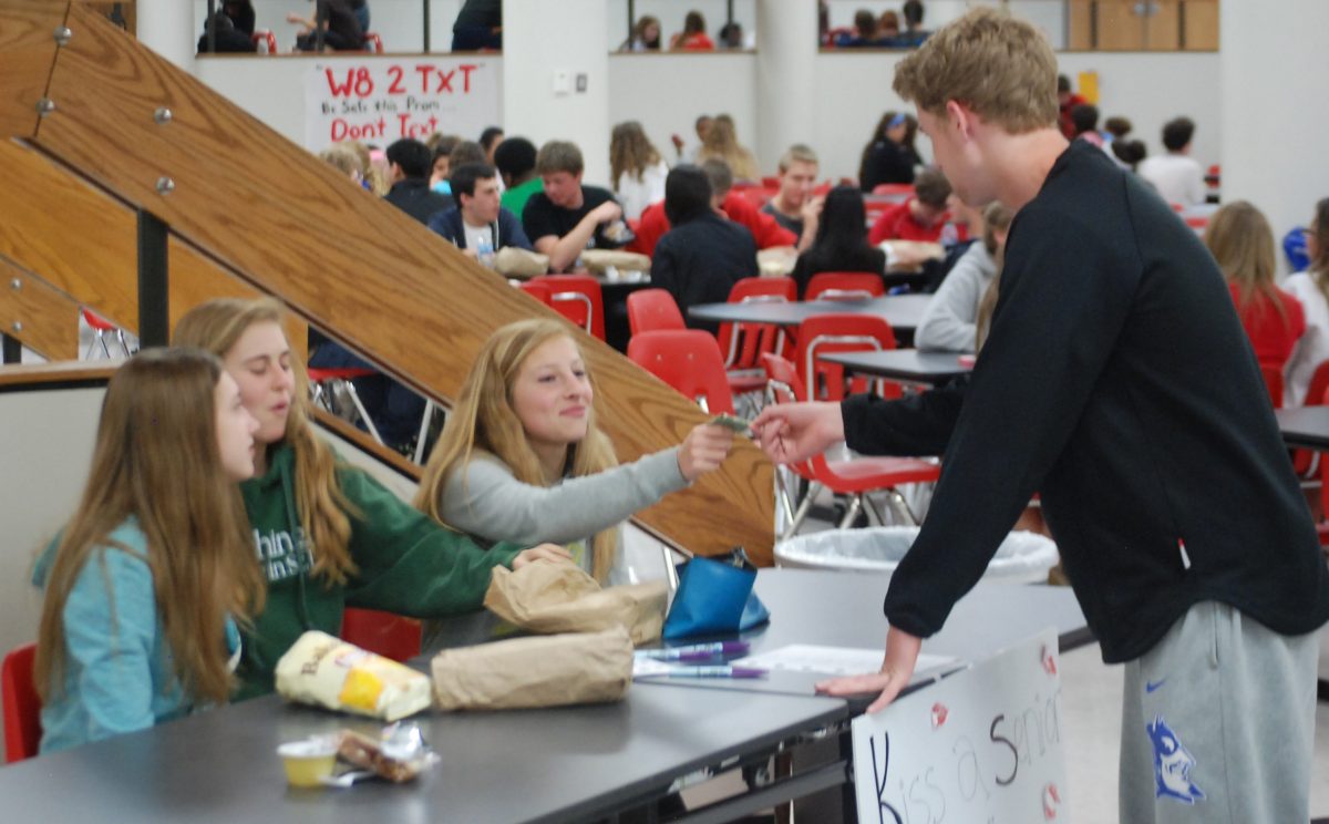 Freshman+Michael+Rembold+buys+a+Hersheys+kiss+gram+for+the+seniors+during+second+lunch.+They+are+being+sold+for+%24.50+each+in+the+commons+during+lunch+and+students+may+include+a+personal+message.+Photo+by+Brandon+Weissman.