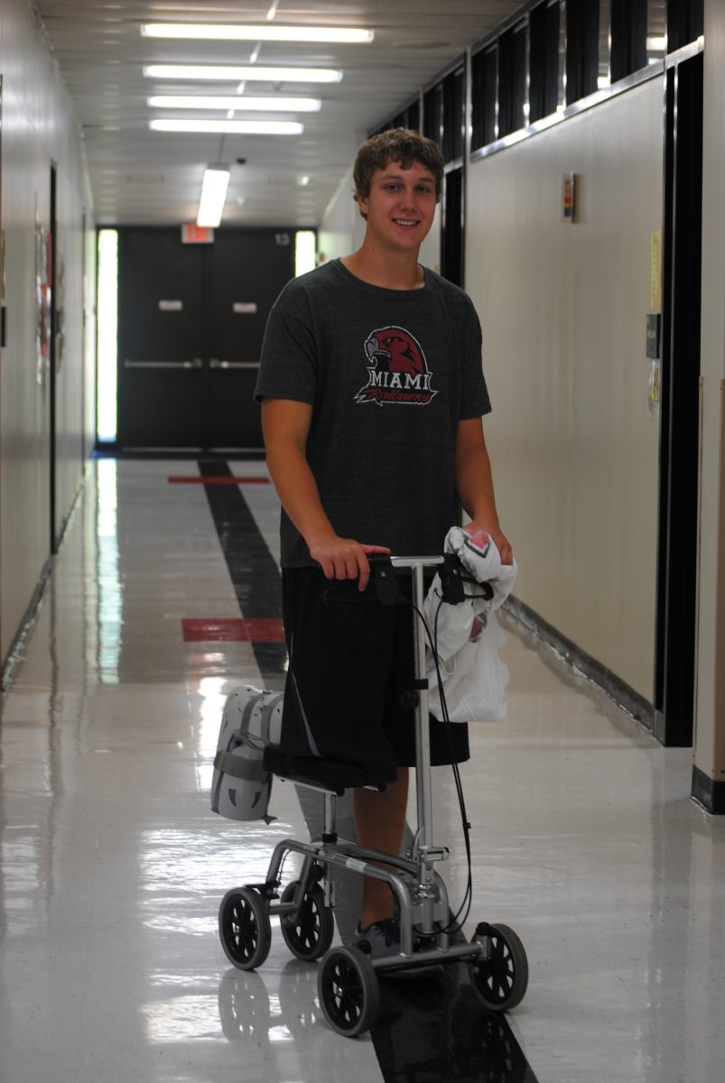 Knes shows off his scooter in the halls while sporting a T-shirt from Miami University in Ohio, where he has committed to playing football. Knes hopes to walk without use of the scooter by the middle of October. Photo by Kelsey Larimore.
