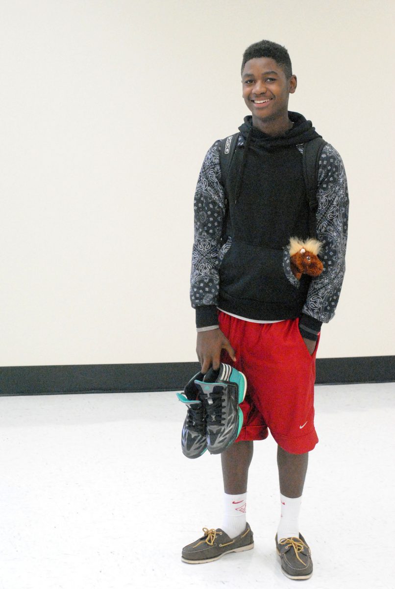 Junior Jeremiah Alberty is wearing Sperrys and holding basketball shoes in his hands. He likes wearing nice shoes, but needs basketball shoes for practice.