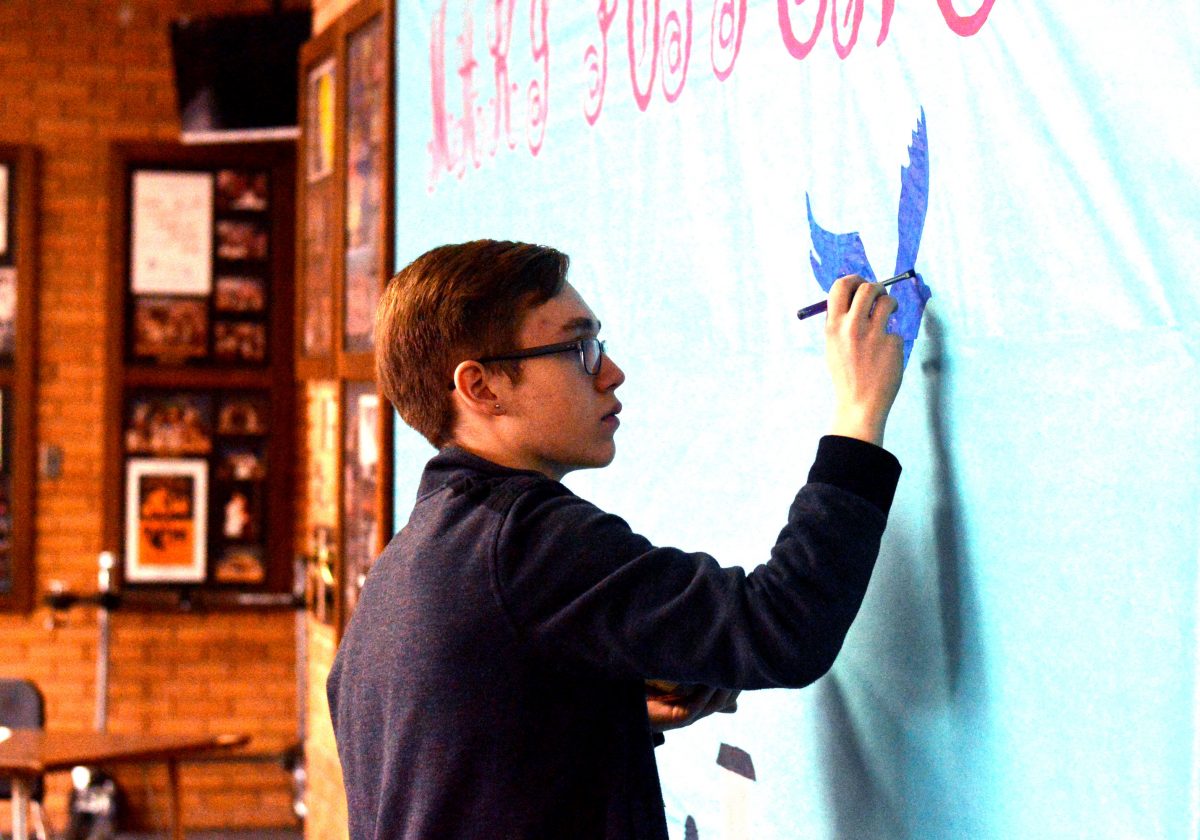 Junior Matthew Kertzman paints the lobby display publicizing the upcoming musical,Mary Poppins.  The show opens Feb. 26.  Photo by Matt Frischer. 