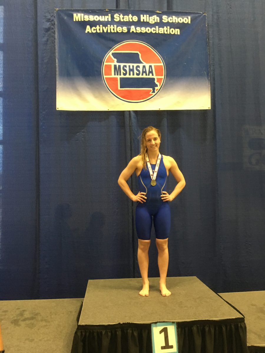 Senior Madison Brown stands on the podium after becoming the State champion for the 100-yard backstroke on Feb. 18 at St. Peters Rec-Plex. “This year it was nerve wracking considering it was my last year of high school swim,” Brown said. “But I just wanted to take it all in and enjoy it.” Photo courtesy of Madison Brown.