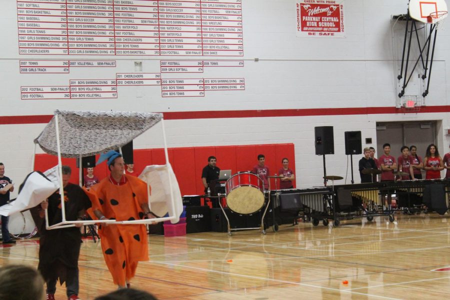 Principal Tim McCarthy and Athletic Director John Theobald dress ass Flintstones characters and ride around in a pretend car as a part of the staff dance at the Homecoming Pep Rally.  