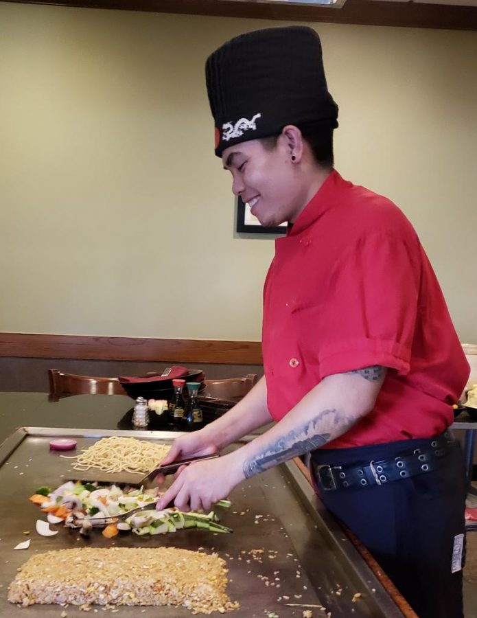 A hibachi chef smiles and laughs with guests as he prepares their meal. Photo taken by Brett Smith.