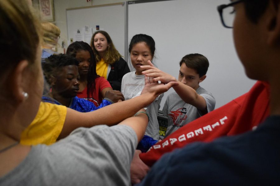 Link Leader Chelsea Baird (11) looks on as (left to right) freshmen Amarion Lorthridge, Chelsea Smith, Lily Liu, and John Mendel participate in the “Human Knot” activity during AC Lab on Aug. 31. The goal is to link arms with someone and by the end of the game untangle the entire group so everyone is standing in a circle.