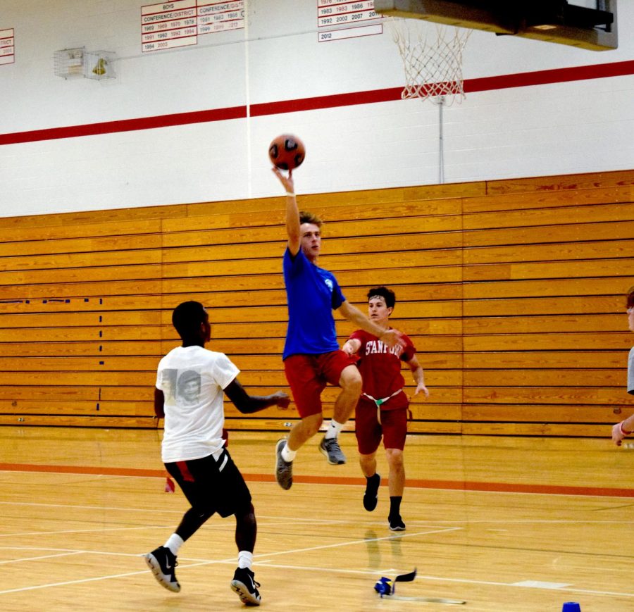 Junior Luke Schaefer jumps for a dunk while senior Jake Moritz pulls his flag during game of Gatorball, a combination of touch football, soccer, and football in competitive sports PE class. 