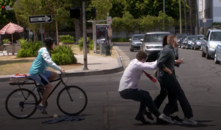 Deluca pulling Jackson and Maggie away from a speeding car, while a teenager on a bike passes  and is about to be hit.