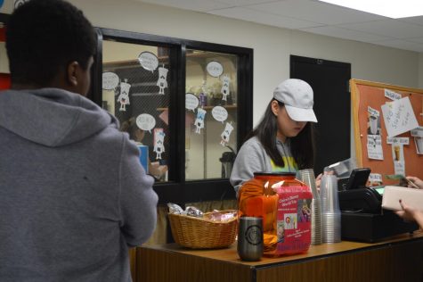 Cafe student manager YuTing Shi places an order sticker on a customers cup.