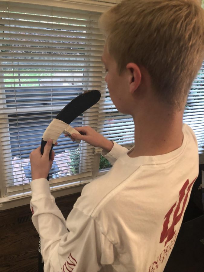 Senior Jonathon Nathan tapes his hockey stick. “No two people do it the same so I don’t trust others to tape mine,’ Nathan said. Photo by Avery Cooper.