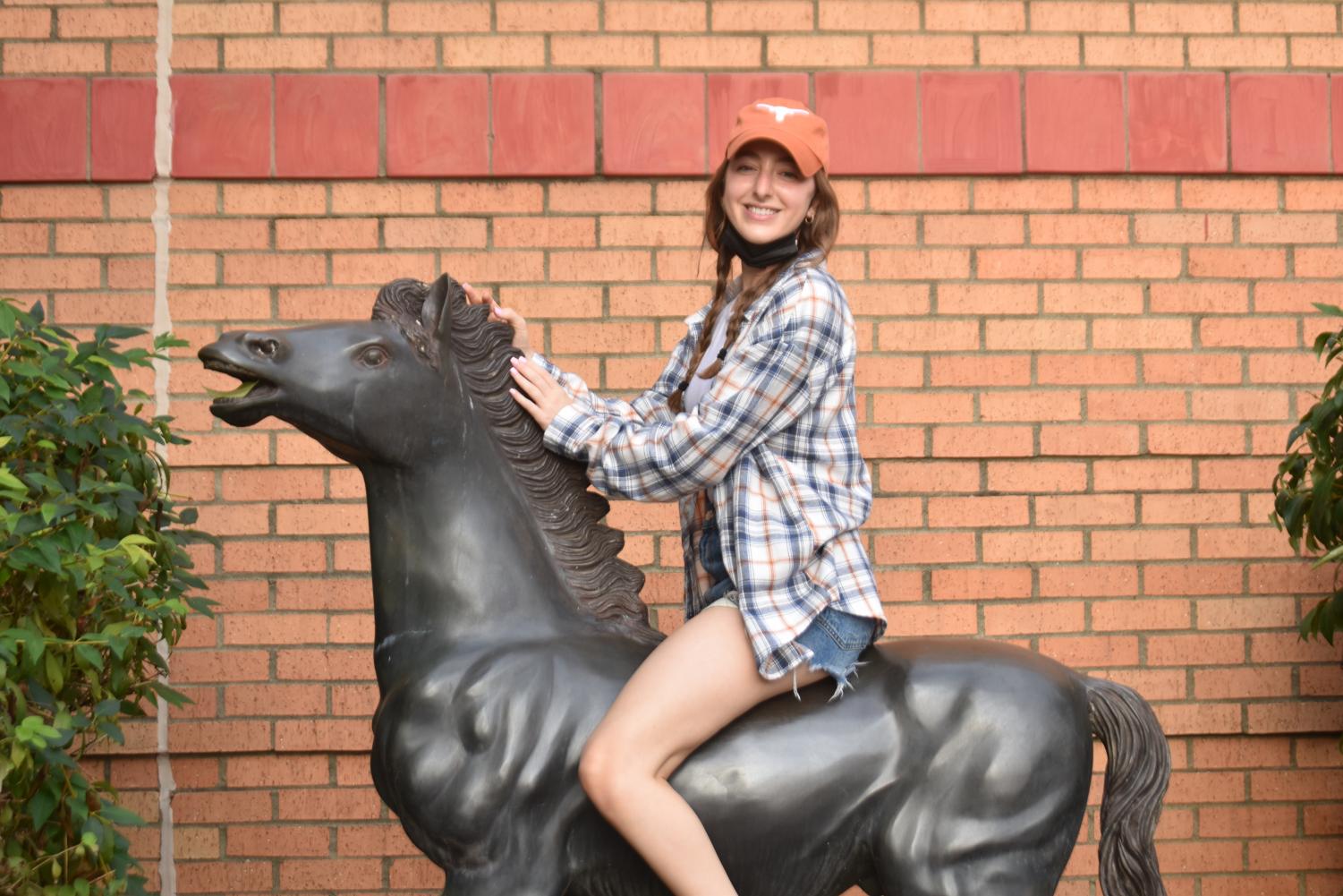Riley Burstein (12) poses on the Colt statue during Class Theme day.  The Homecoming theme is candy, and the senior class theme was Jolly Ranchers so many dressed up as cowboys and cowgirls. 