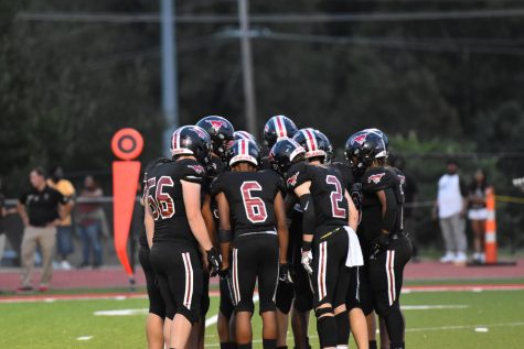 The football team huddles together at their game against Rockwood Summit High School on Sept. 10. Photo by Kayelyn Tate.  