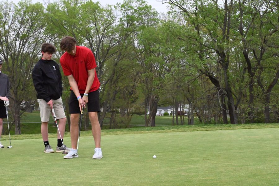 Senior Jack Carroll hits his par putt on hole 7 at Four Seasons Country Club while senior Will Edwards gets a putt read behind him. Photos by Christine Stricker.