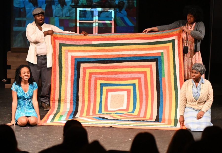 Sophia Randolph, Chris Robinson, Jordyn Williams, and Kiera Anderson-Pittman holding up the replica of a Gee’s Bend quilt. 