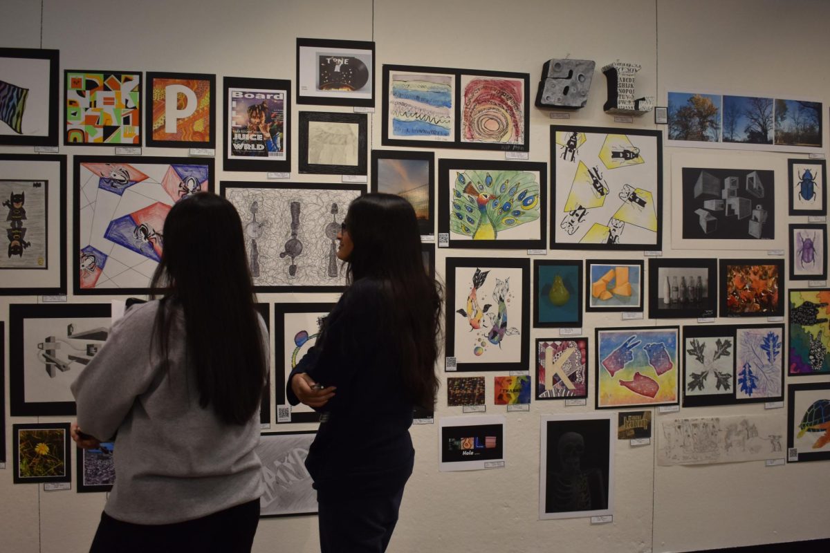 Students walk around the art gallery  admiring the work of their fellow students during The Art Show. Work from Ceramics, Design Arts and AP Drawing as well as others were featured in the show on Jan 8.