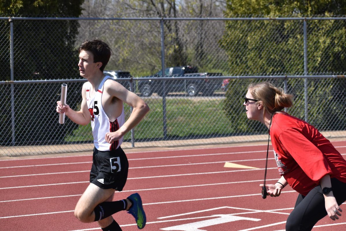 Distance+coach+Hannah+Merriman+yells+at+Varsity+Cross+Country+and+Track+Runner+Colin+Recar+%2812%29+while+he+is+running+the+4x800+meter+relay+on+March+28.+Recar+ran+2%3A13%3A15