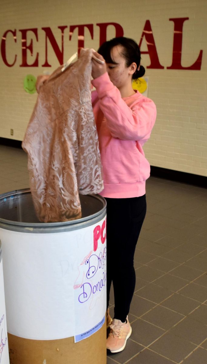 Senior Alyssa Davis places her old homecoming dress in the designated bins in the PCH Commons for the Cinderella Dress Drive on March 11.