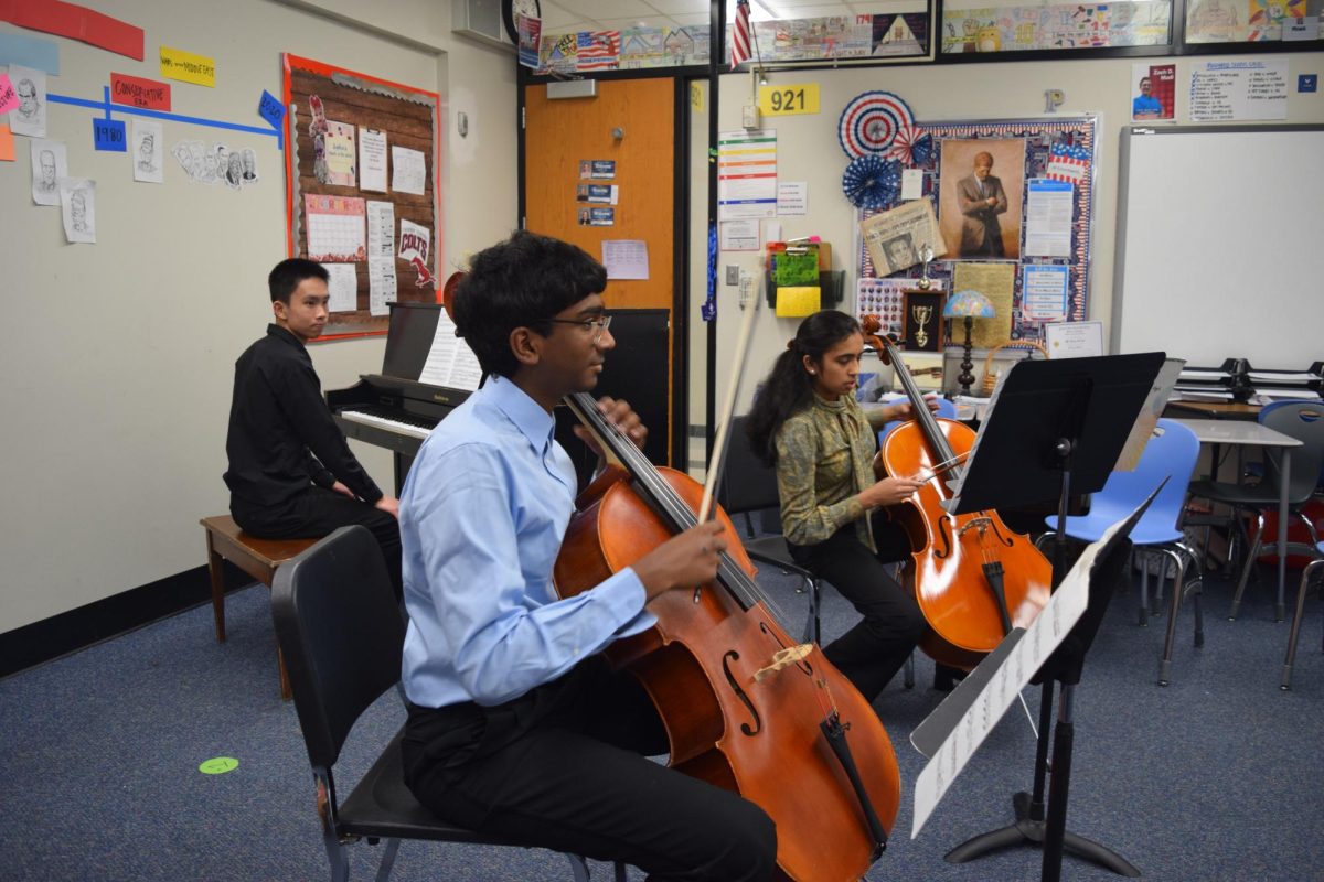 Jason Mathew (9) and Hannah Mathew (11) tune their cellos before playing a duet accompanied by Asher koh (11) on March 8. 