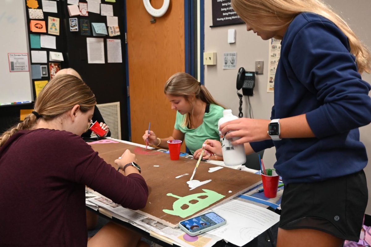 Seniors Maddie Sevasko, Jamie Sevasko, Brooke Williams, and Paige Fraser paint a "Toy Story" themed ceiling tile during Jeff Rogers' College Composition class.