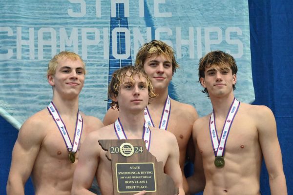 Nathan Malt (11), Hunter Deuschmann (11), Connor Muran (10), and Cole Smith (12) stand on the podium after their 1st place win in the 200 Medley Relay.