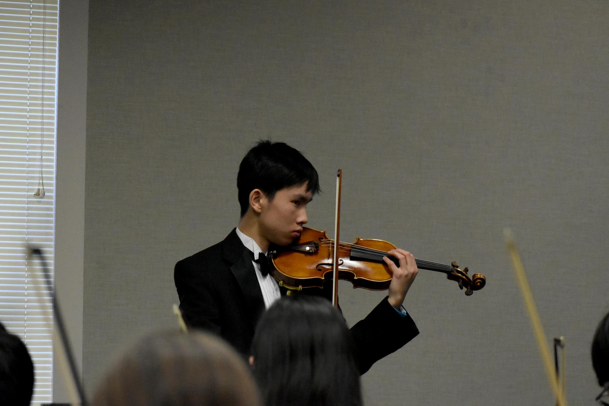 Asher Koh (12) leads the orchestra in tuning their instruments before the performance on Jan. 30. Koh has perfect pitch and assists the orchestra to play on pitch. 