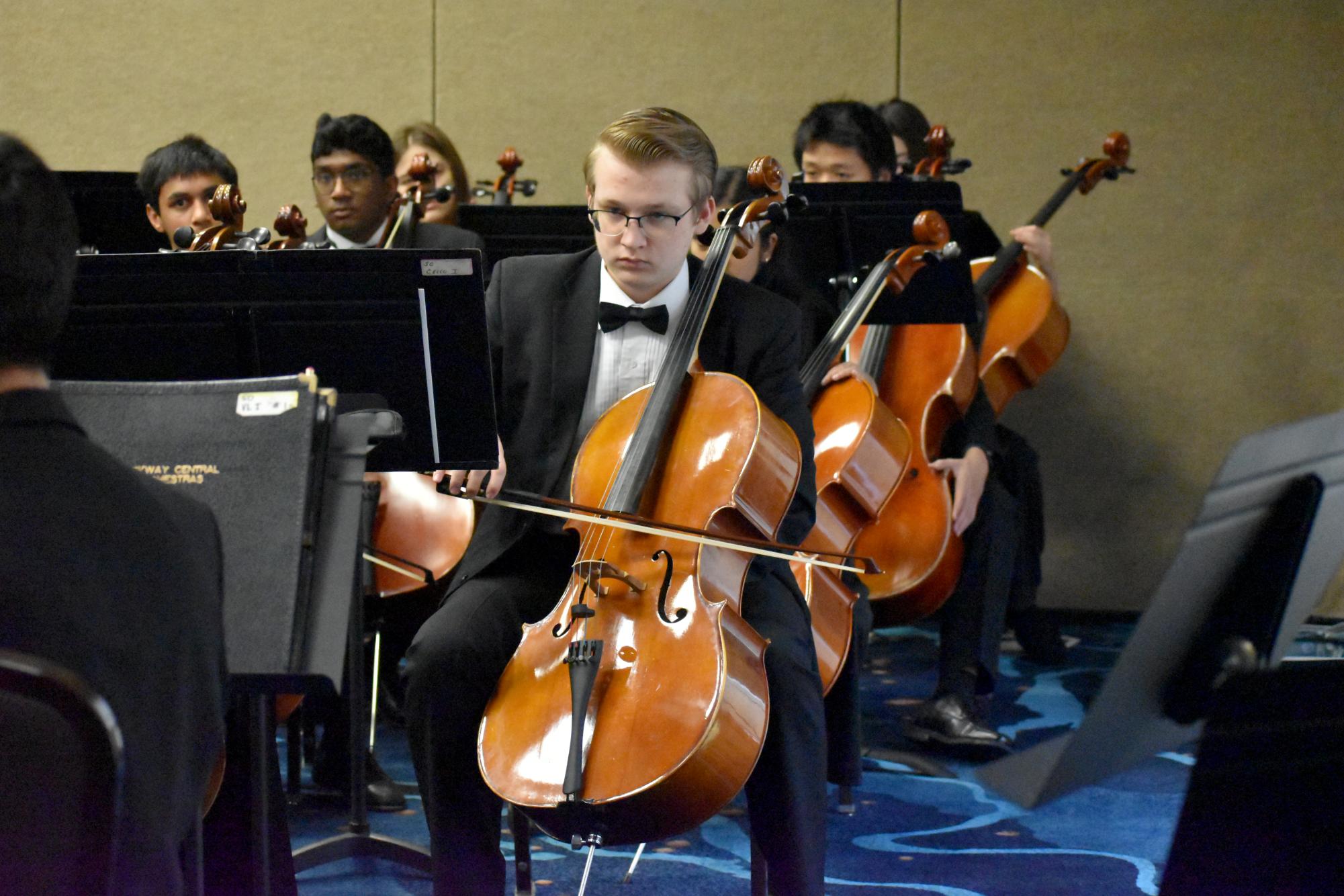 Zach Madi (12) plays the cello during warm-up before the performance at MMEA on Jan. 30.