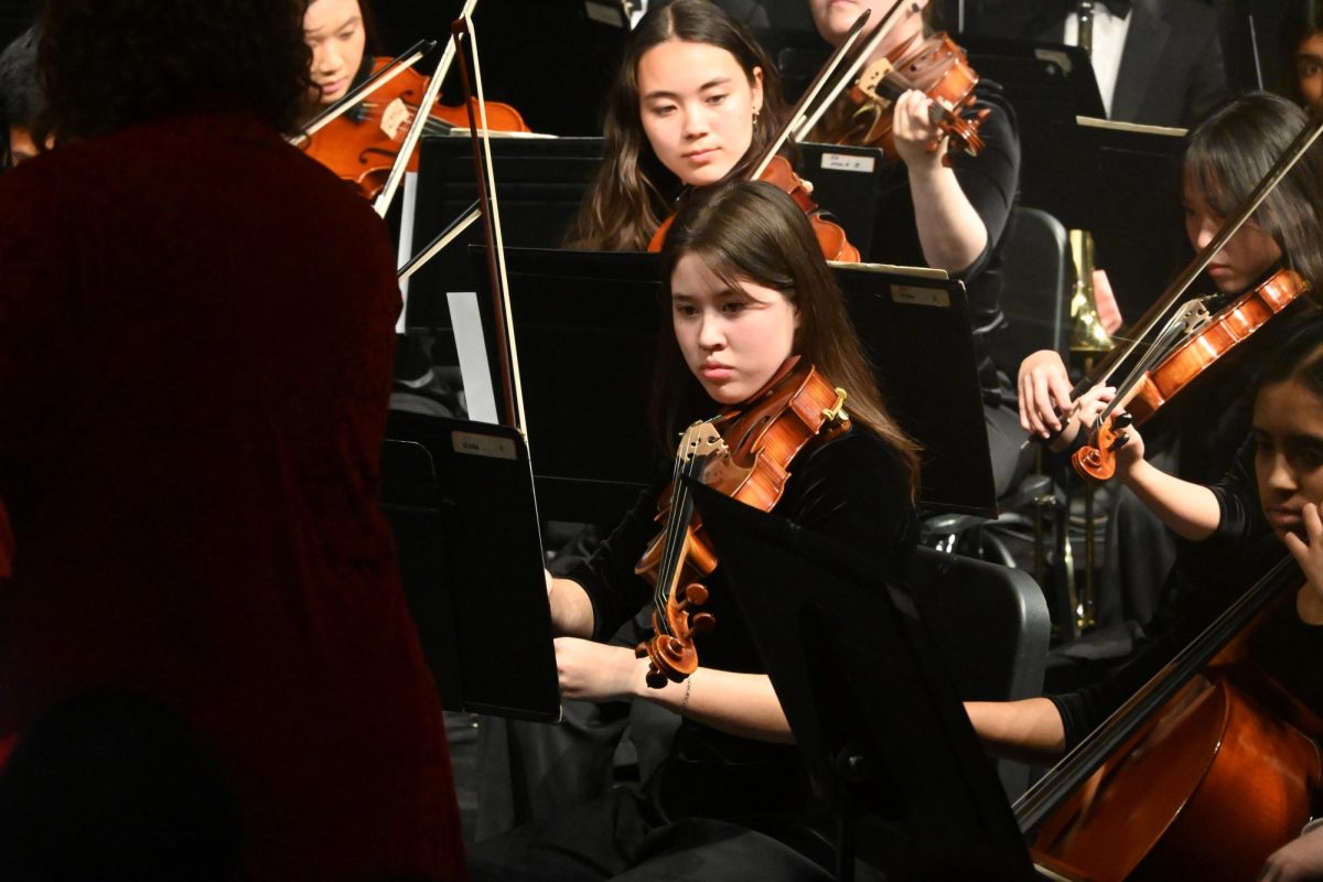 Macey Heimburger reads her music to prepare for the next song at the Orchestra concert on April 30.  