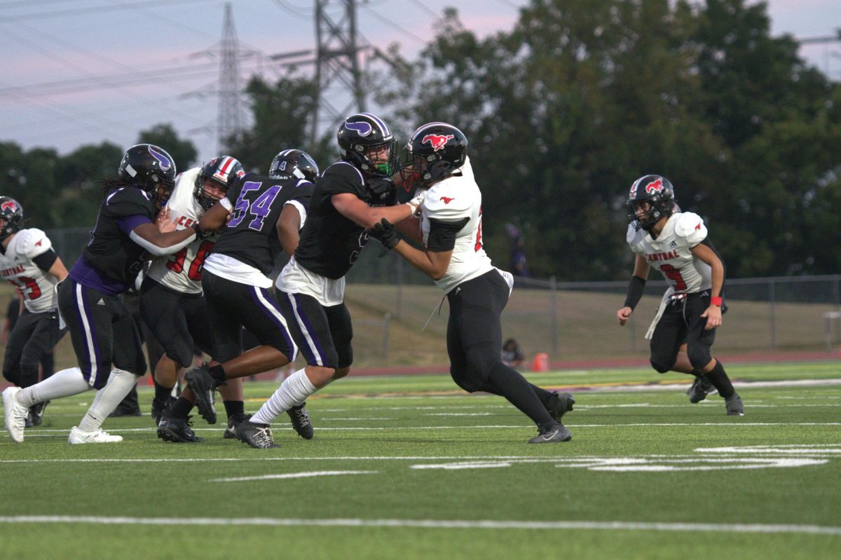 Number 77 Christian Wood pushes hard against his opponent, using all of his strength to try and take him down. With his intense focus and effort, he's determined to make the tackle and help his team.